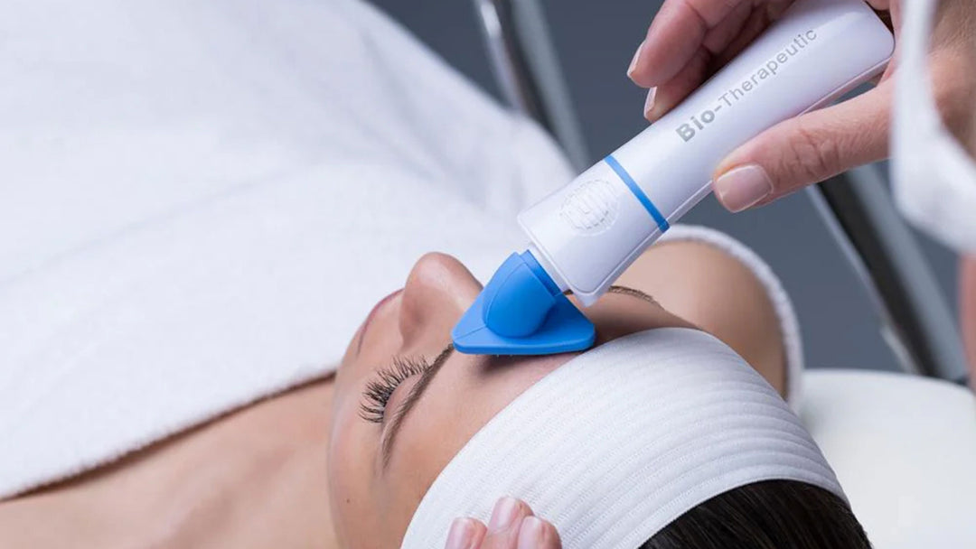 Person receiving a facial treatment with a Bio-Therapeutic device on a white background.
