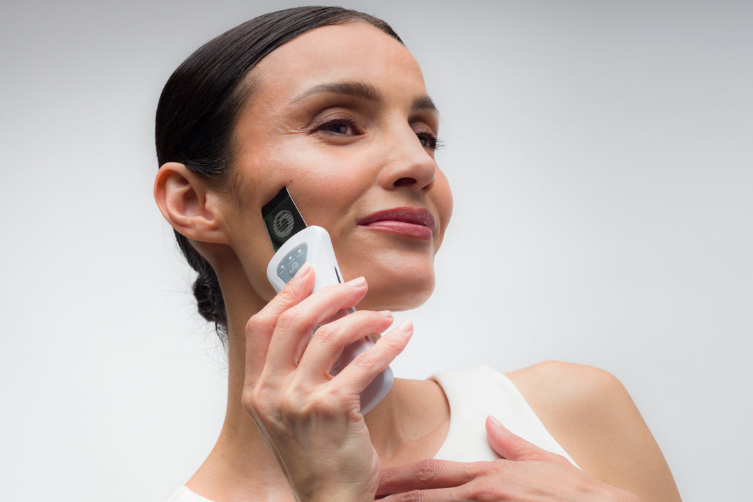 Woman holding a Bio-Therapeutic bt-micro fusion device on her face against a gray background