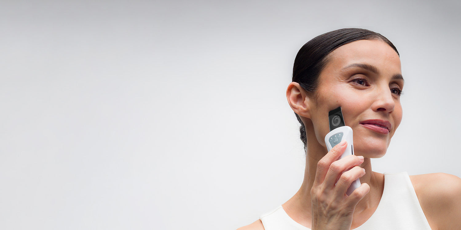 Woman holding a Bio-Therapeutic device against a light gray background